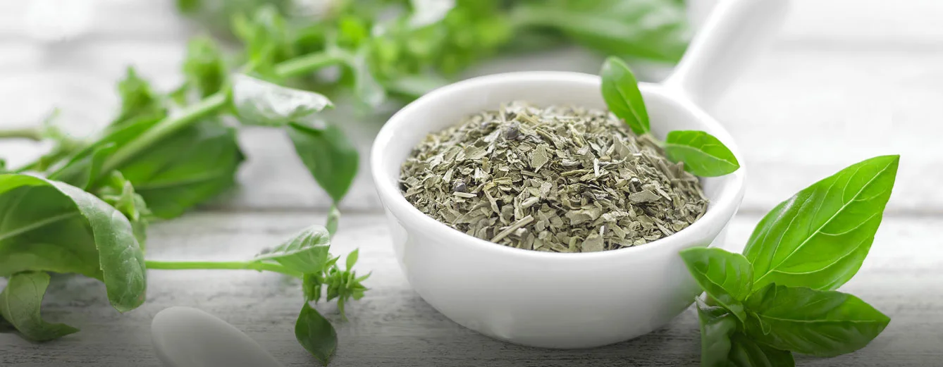 Fresh leaves and a bowl of dried botanical herbs
